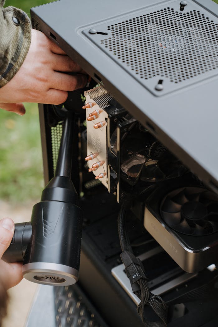 Close-up of hands cleaning the interior of a PC case with a duster, focusing on computer care and maintenance.